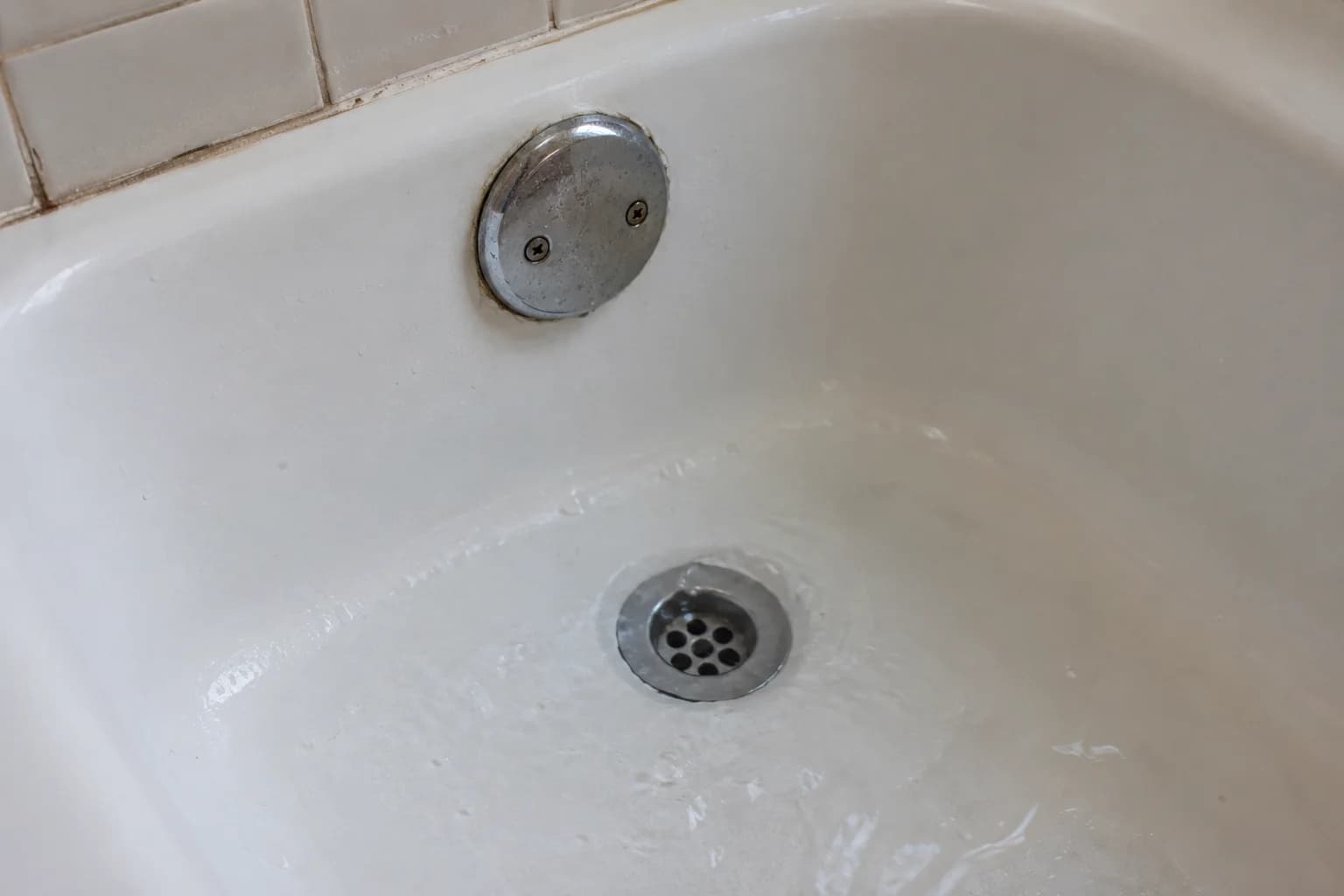 Bathtub drain and overflow fitting with a small amount of standing water